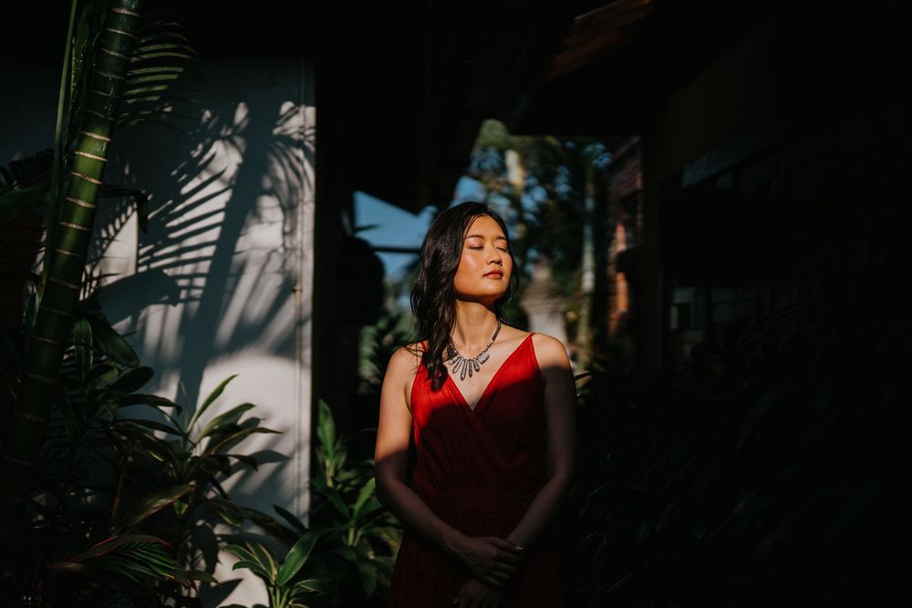 Artistic shadow play frames a red dress in a tropical garden setting.