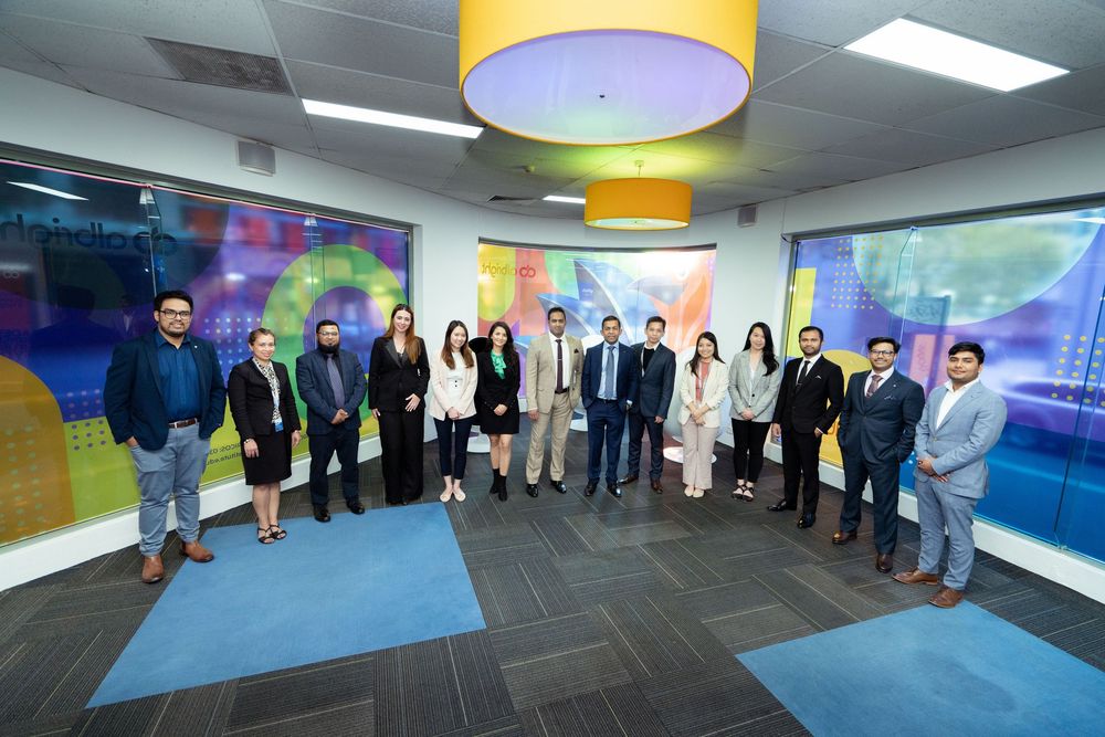 Wide view of employees standing together in a modern office space with colorful accents and displays.