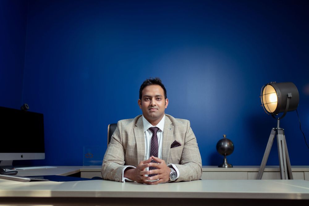 Executive seated at a minimalist desk against deep blue walls with ambient lighting setting a professional mood.