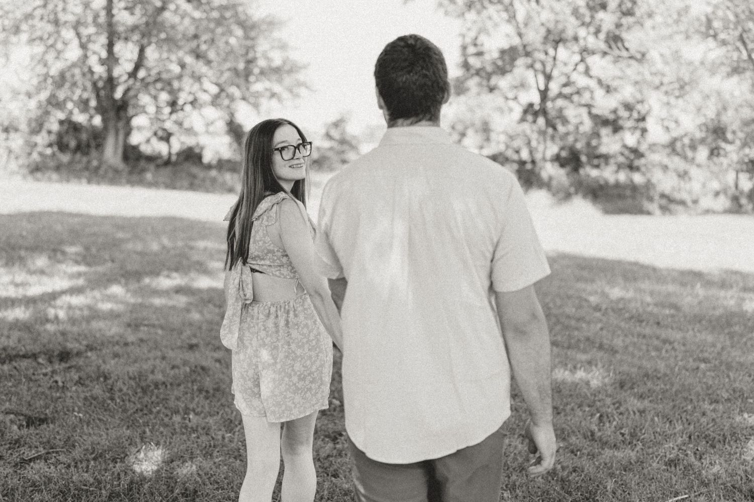 A couple walks hand in hand through a scenic garden path during a sunny day.