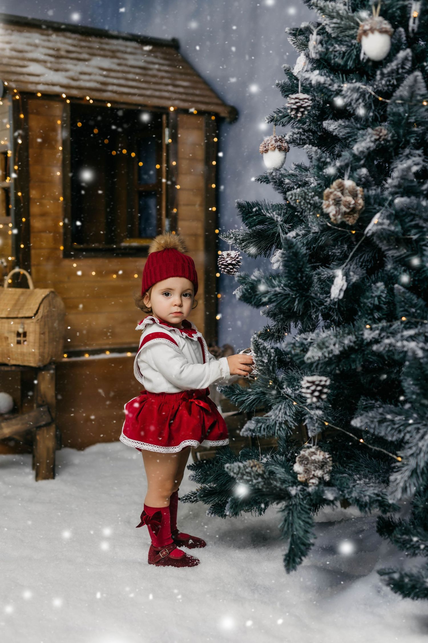Niña posando junto a un árbol de Navidad decorado durante una sesión de fotos navideña.