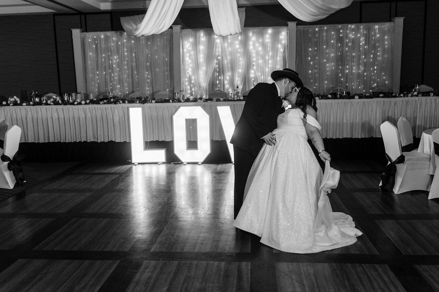 A wedding reception venue decorated with elegant white drapes and sparkling string lights creating a romantic ambiance.