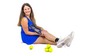 Tennis athlete in blue uniform sitting with tennis balls and racquet.