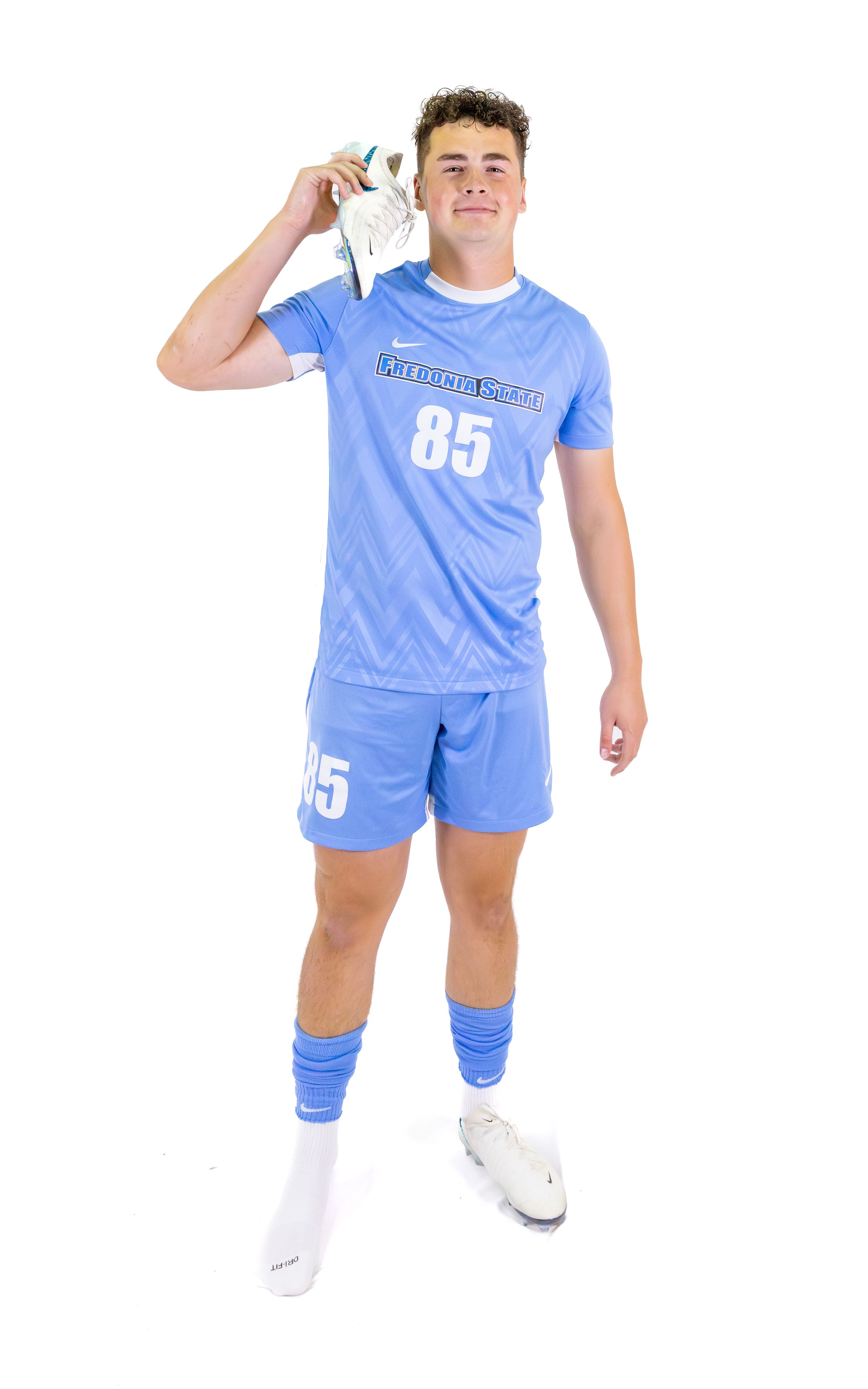 Soccer player in light blue uniform with number 85 posing with hand raised against white background.