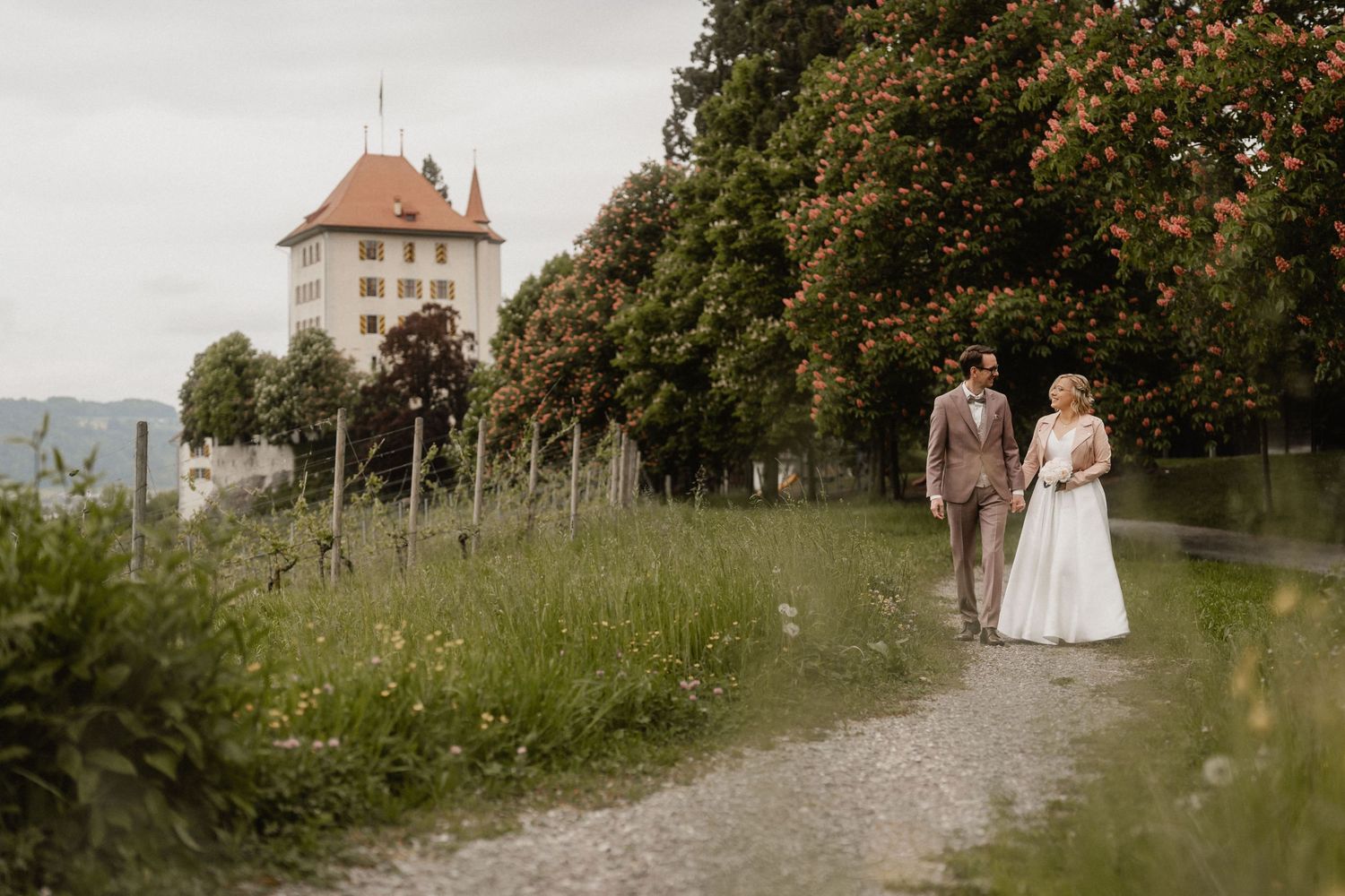 Couple enjoying an intimate moment in a rustic garden setting with stone architecture and lush greenery in the background.