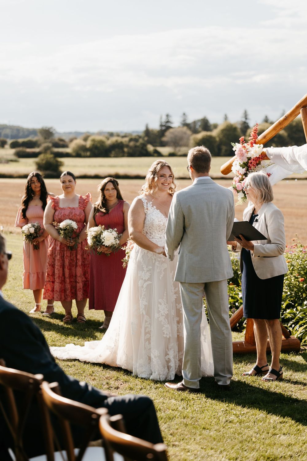 Wedding party lines up outdoors in front of scenic countryside view on a sunny autumn day.