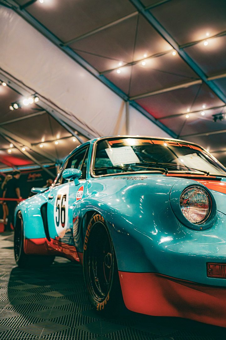 Close-up sequence shots of a vintage turquoise racing car showing front details in indoor lighting.