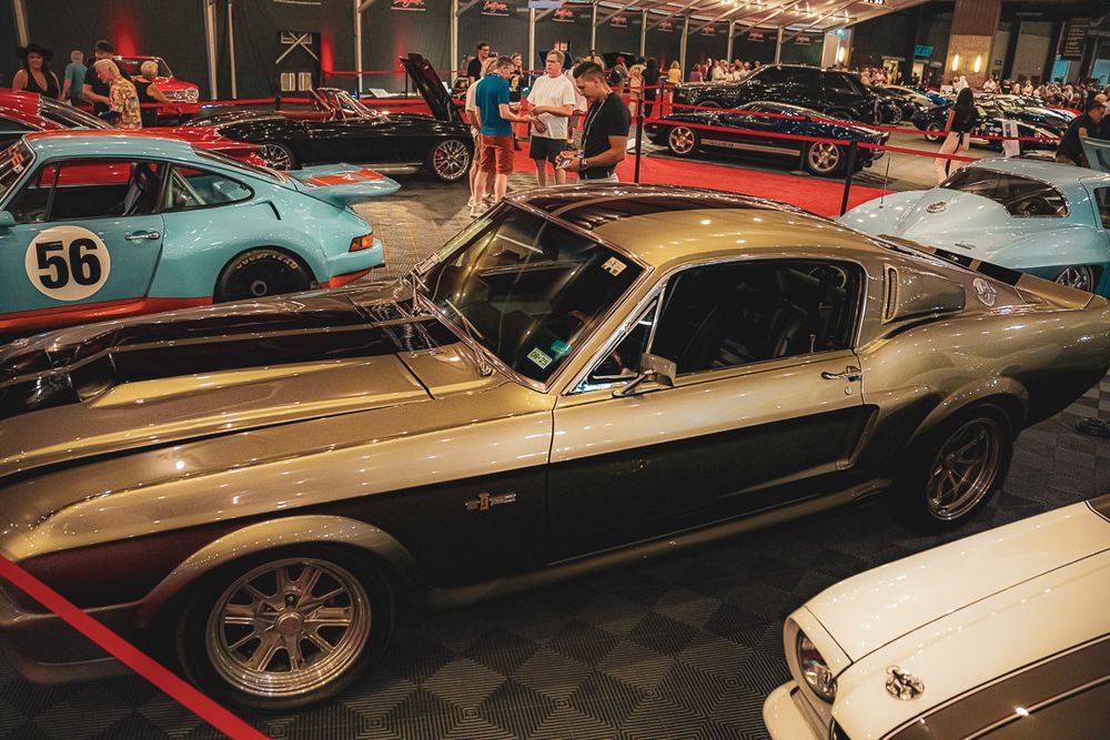 Multiple classic race cars displayed in a line at an indoor automotive museum or showroom.