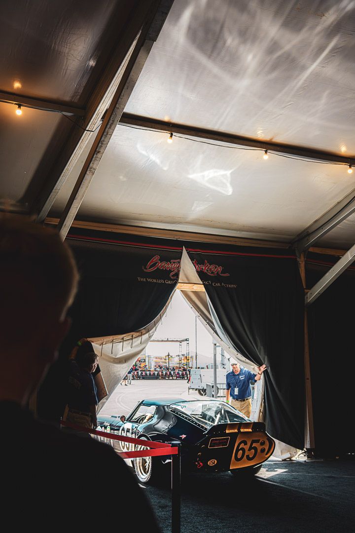Classic racing car number 652 displayed under white tent with dramatic side lighting.
