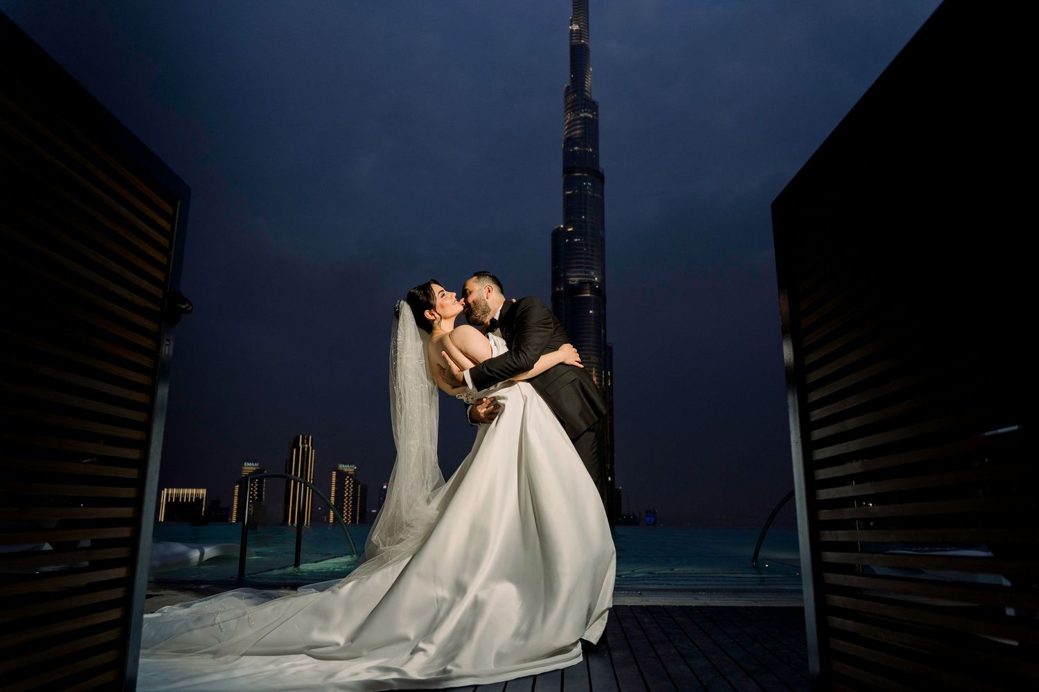 A bride in a flowing white wedding dress with an elegant veil blowing in the soft light of sunset.