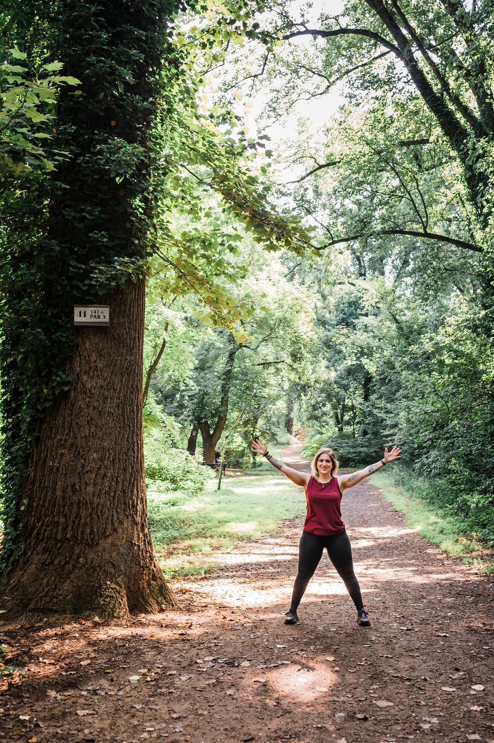 Three connected forest path photos showing a person in a red sweater joyfully posing with outstretched arms among autumn trees.