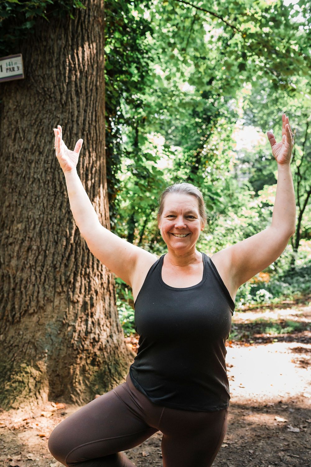 Person demonstrating joyful yoga expressions and poses surrounded by tall trees in a peaceful woodland setting.