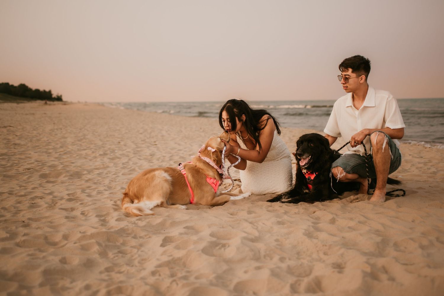 Couple relaxing on sandy beach at sunset during romantic photoshoot.