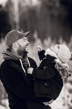 A black and white photo series showing a parent lifting and playing with a small child outdoors.