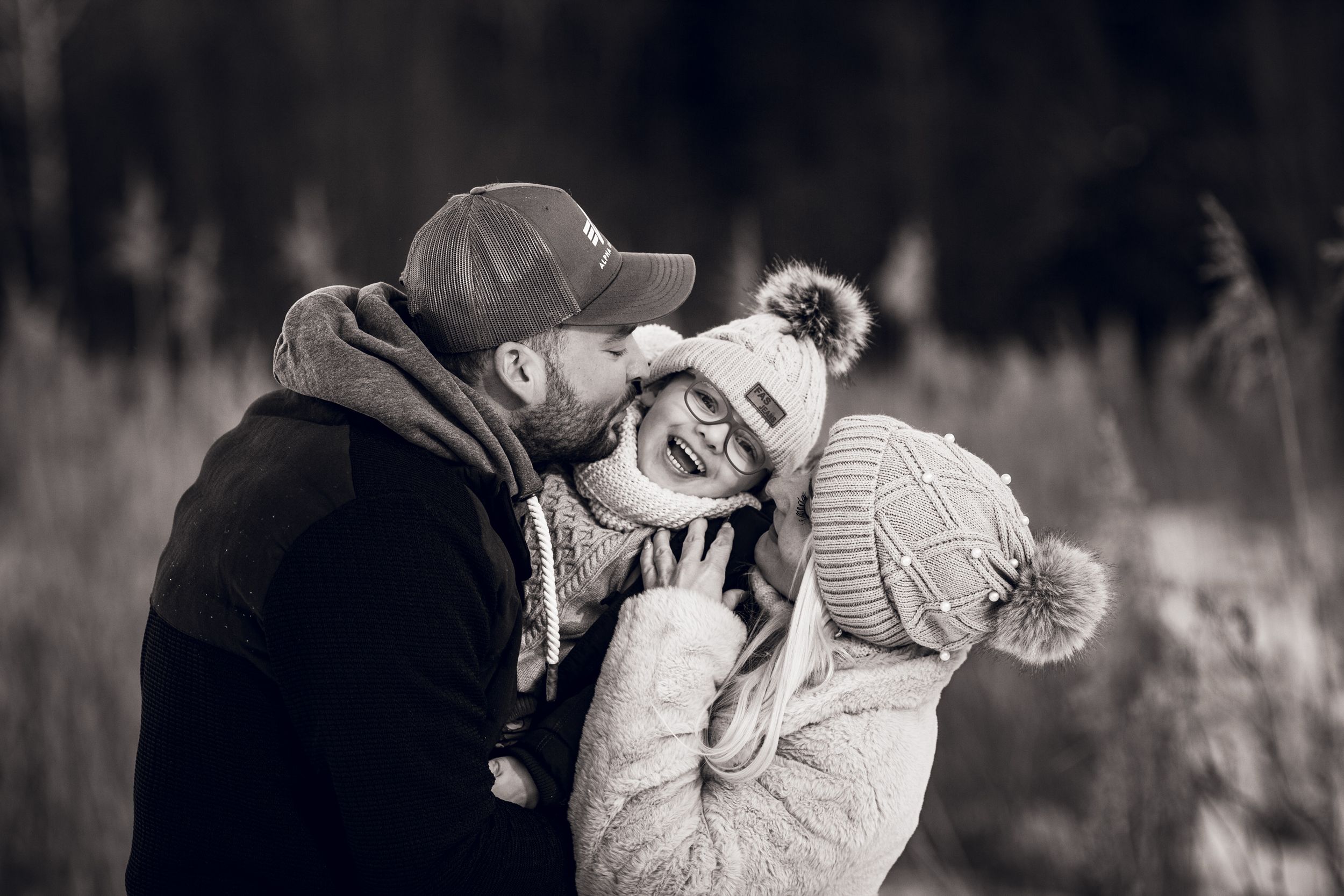 Intimate black and white winter portrait of couple in knit hats sharing a tender moment outdoors.