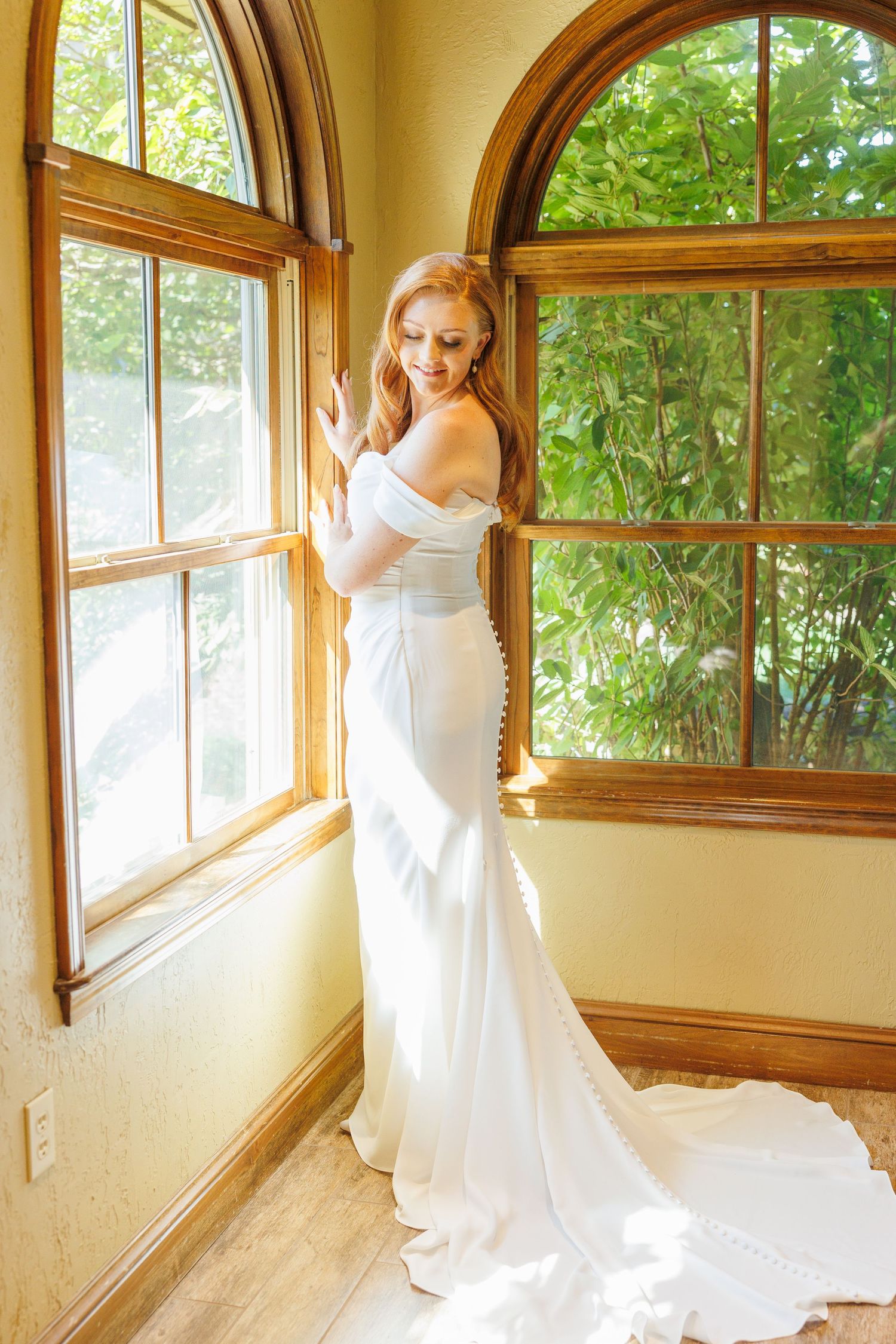 Elegant flowing white wedding dress displayed across multiple window panels with natural light streaming through at Big Cedar Lodge.