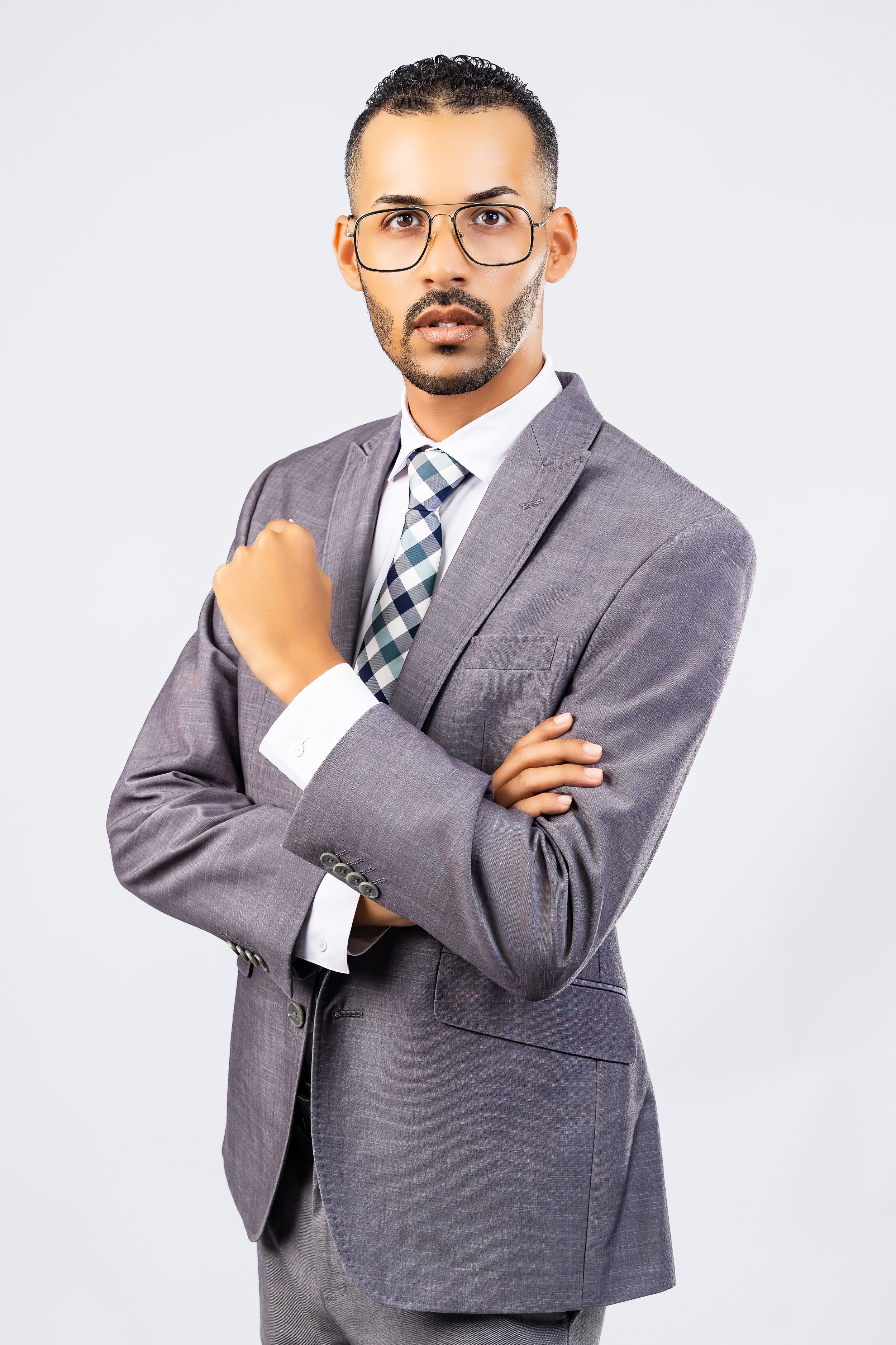 Professional man in gray suit and tie with glasses posing with arms crossed.