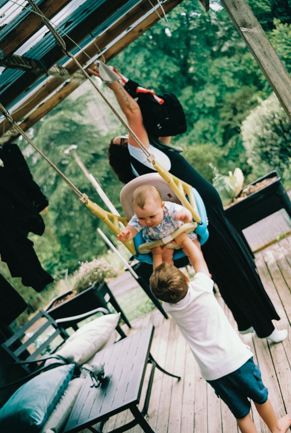 Children playing and climbing on outdoor wooden playground equipment on a sunny day.