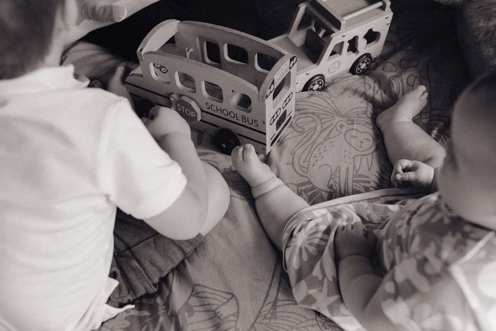 A child plays with a toy truck while lying on their side in a black and white photograph.