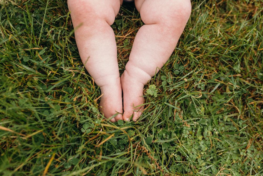 Close-up of bare feet resting on green grass.