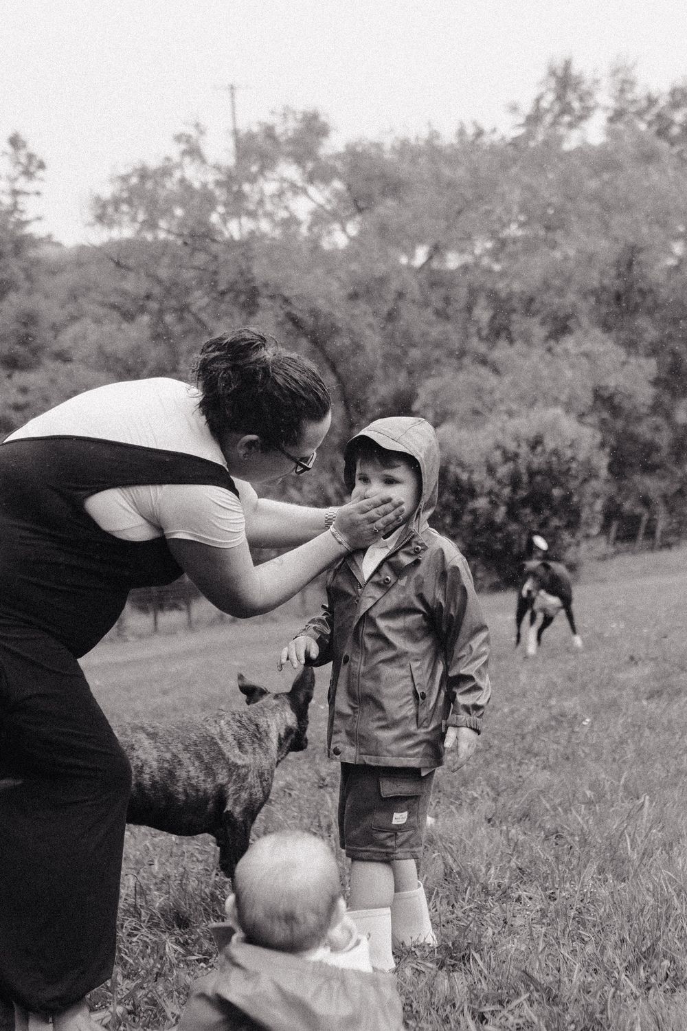 A sequence of black and white photos showing someone being splashed with a liquid outdoors in a grassy field.