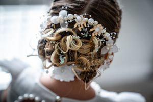 Delicate white floral accessories and baby's breath adorn an elegant bridal updo hairstyle.