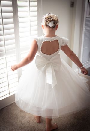 A series of connected photos showing a white flower girl dress with tulle skirt and delicate details against window light.
