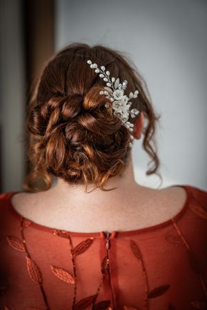 Close-up view of an elegant bridal hairstyle decorated with delicate white floral hair accessories against a red dress.