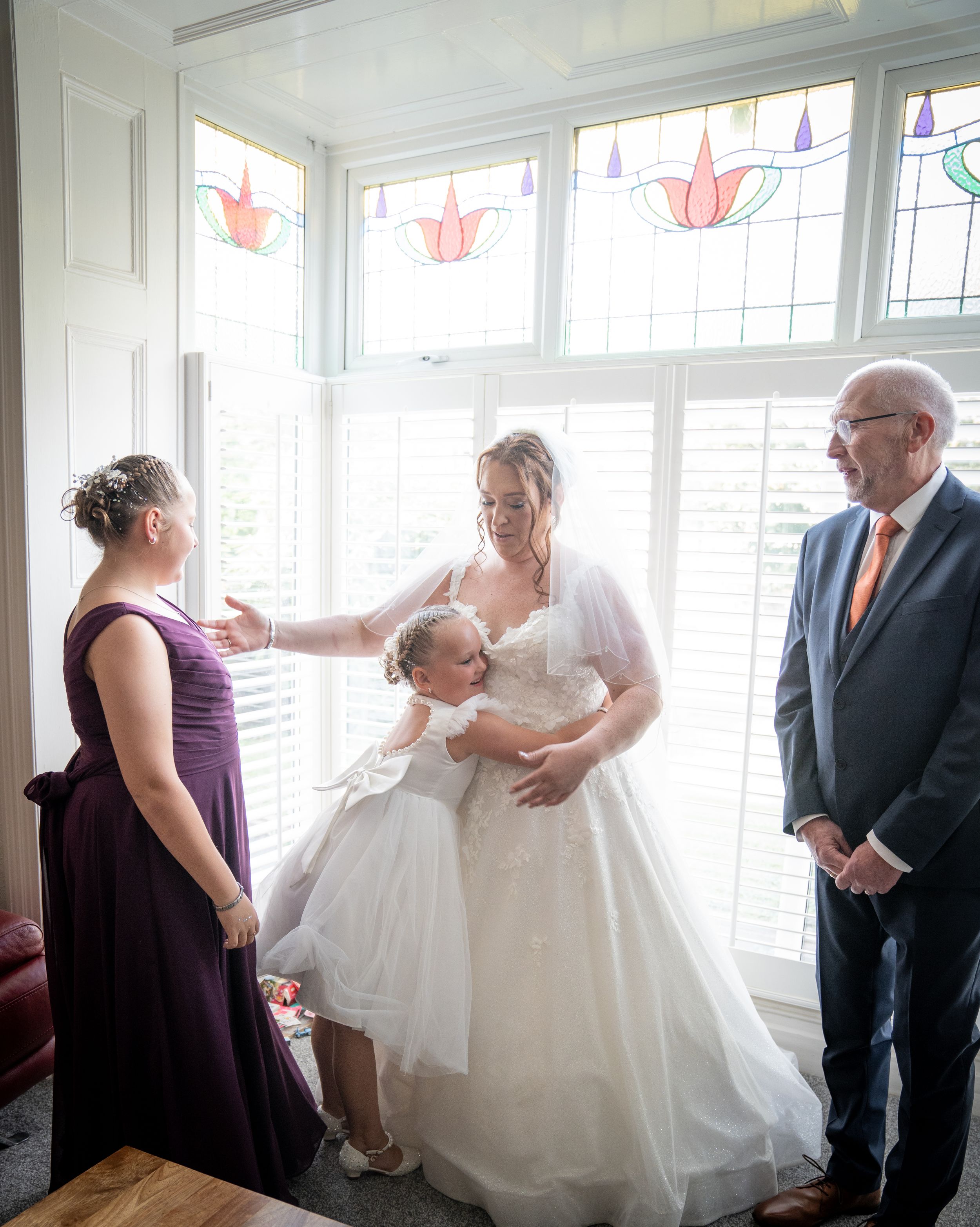 Panoramic series of candid wedding moments showing intimate family interactions in a sunlit room with stained glass windows.