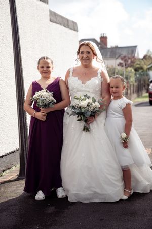 Wedding party in purple and white dresses pose together outdoors for elegant group photos.