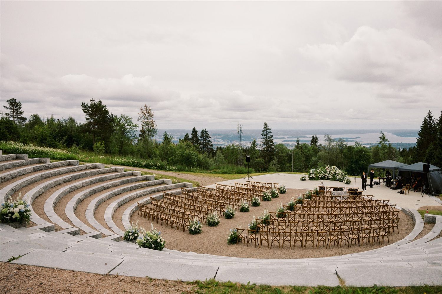 Mountains rise behind an amphitheater-style seating arrangement at a destination with curved wooden benches and grass steps.