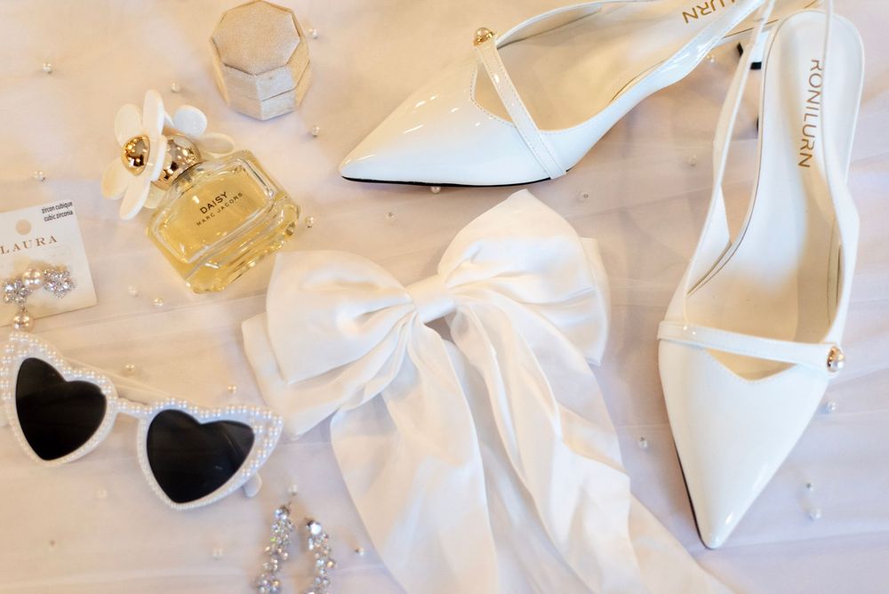 Wedding accessories including white bows, heart decorations, and delicate details arranged on a light surface.
