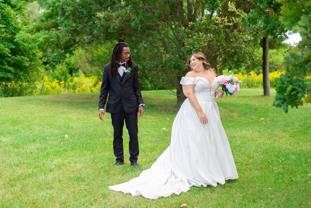 Wedding couple walks and poses together in a lush green garden setting on their special day.