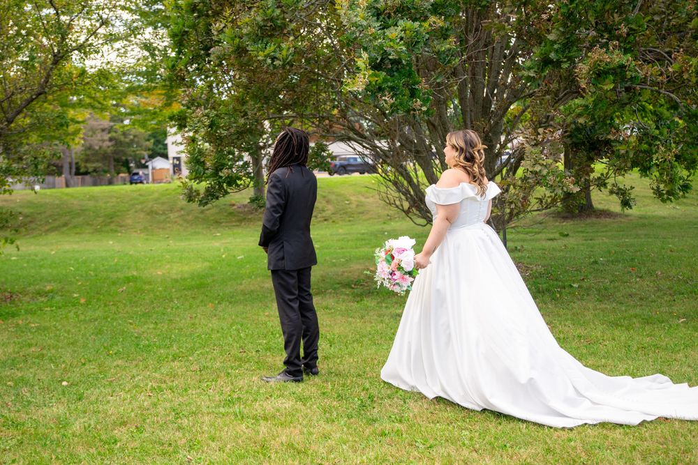 A couple takes wedding photos in a lush green garden setting with the bride in a flowing white gown.
