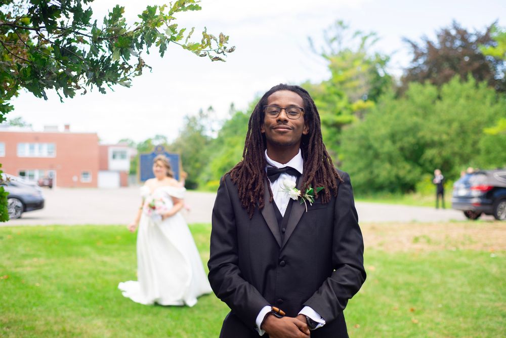 Wedding party members in formal attire taking casual photos outdoors in a park setting.