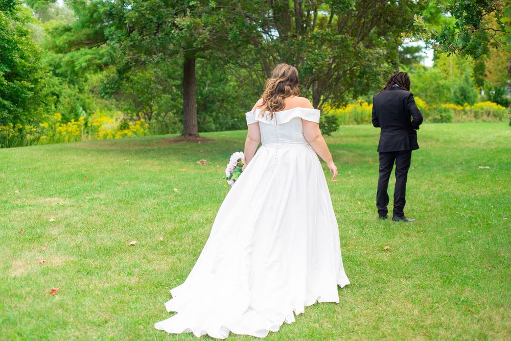 Wedding party posing for outdoor photos on a lush green lawn in summer.