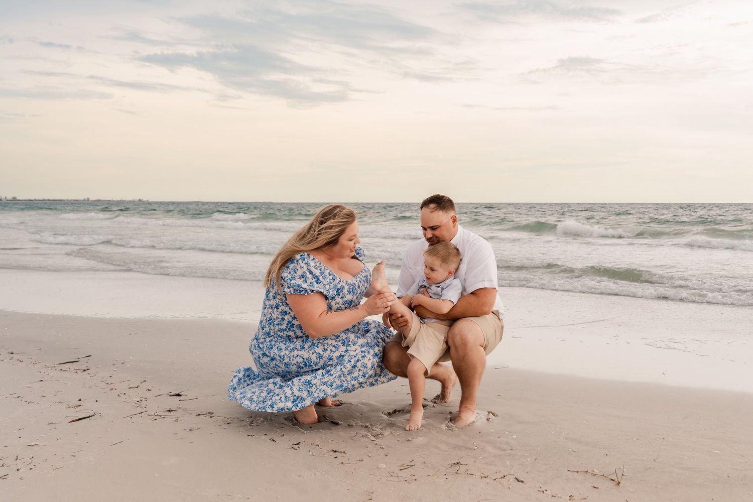 Family photo session on a sunny beach with candid moments and natural interactions.