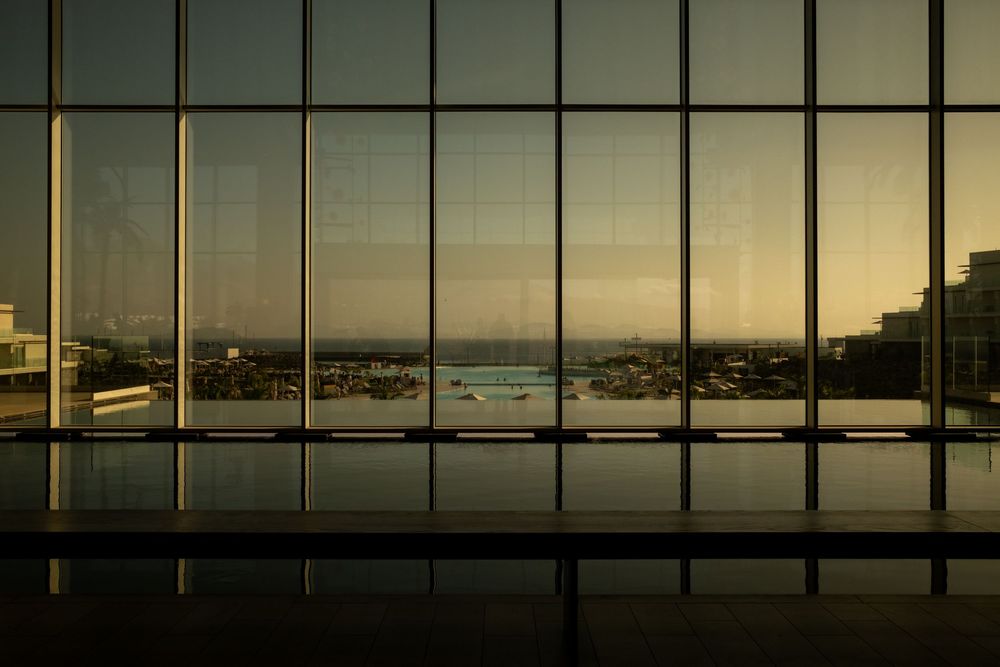 Panoramic window view of a coastal landscape during golden hour.