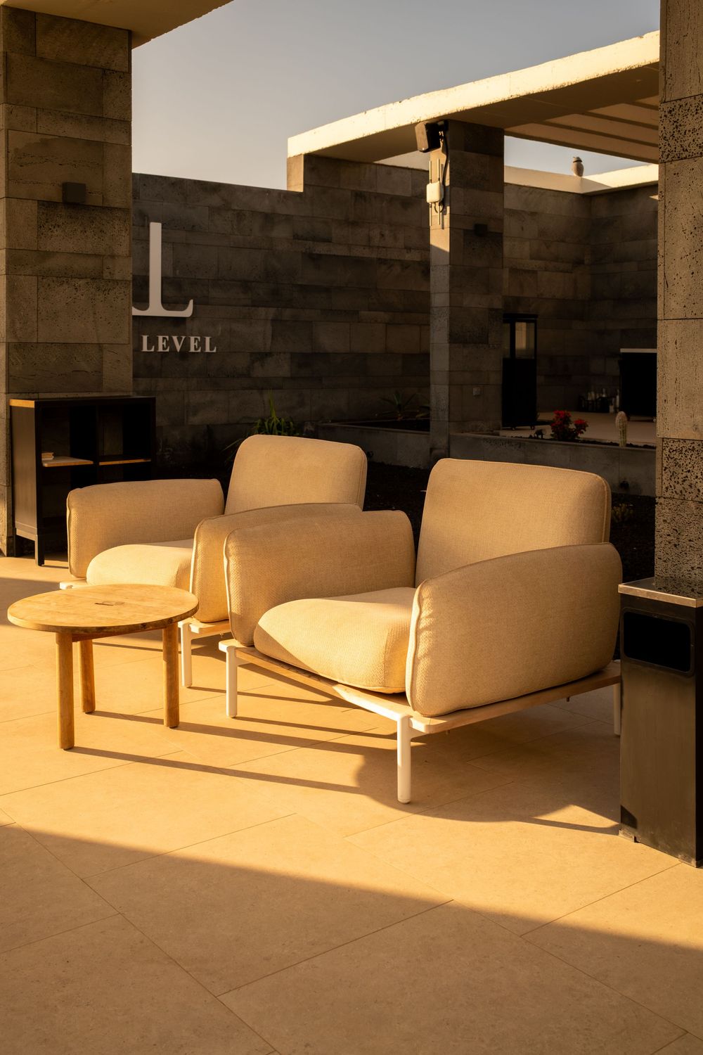 Modern lounge area with cream-colored sofas and stone walls in warm lighting.