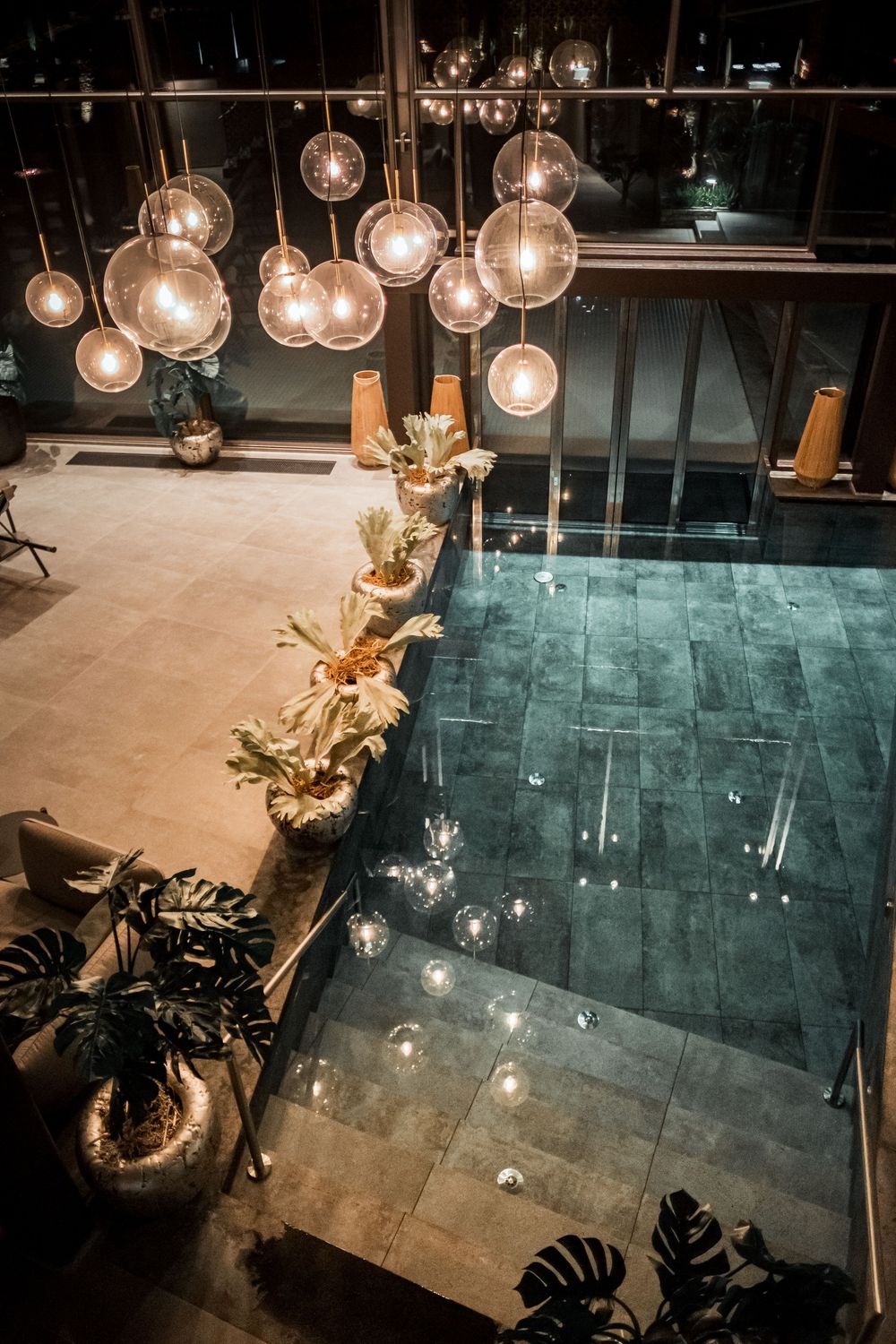Contemporary space with hanging glass pendant lights and tropical plants creating dramatic lighting effects.