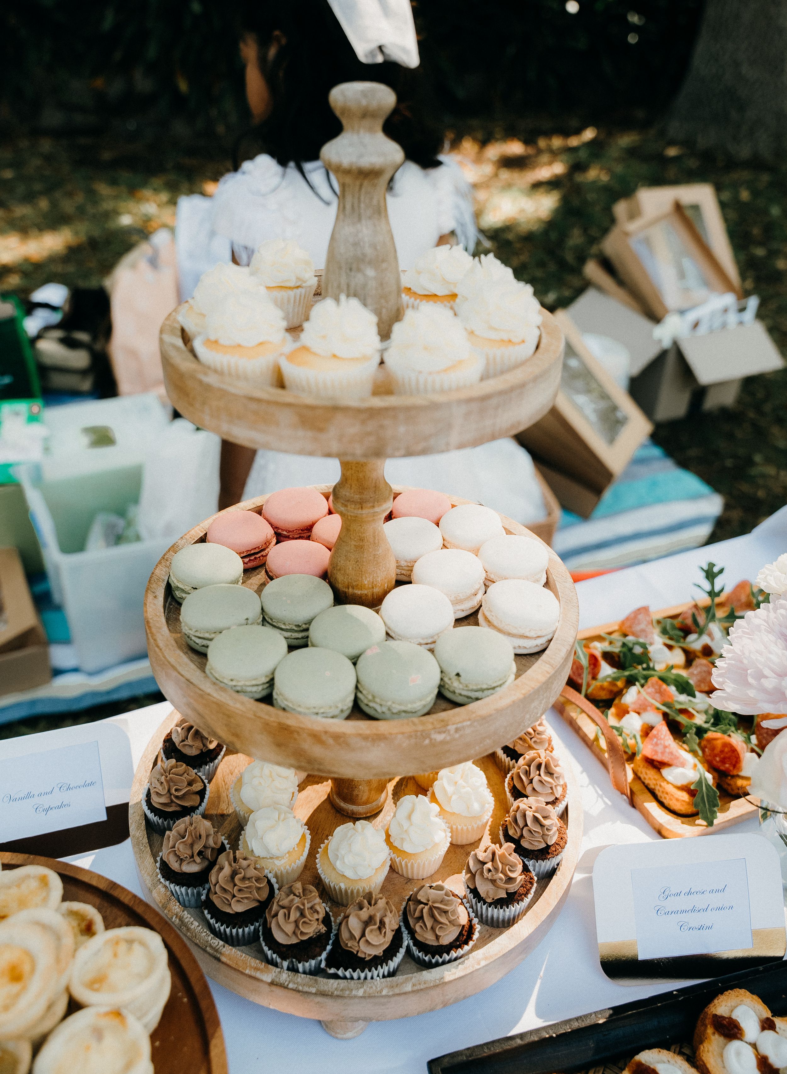 Elegant wedding dessert table with tiered cake stands displaying an assortment of pastel macarons and chocolate cupcakes.