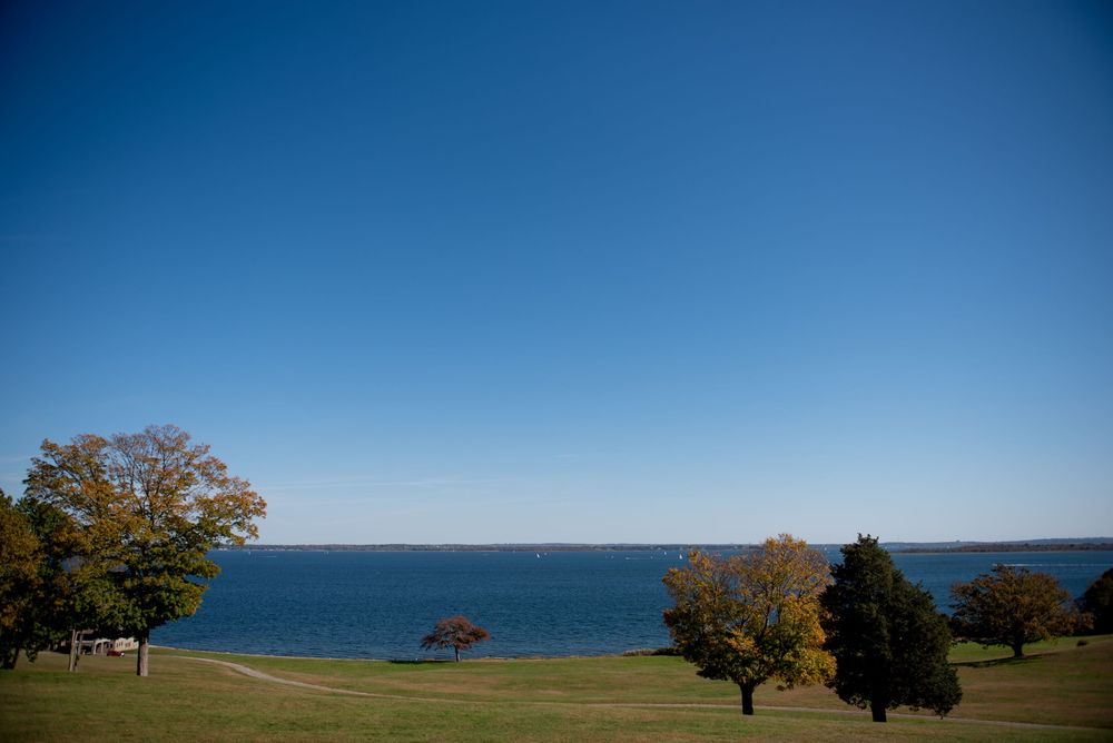 Panoramic ocean view with blue waters meeting clear skies and autumn trees along the coastline.