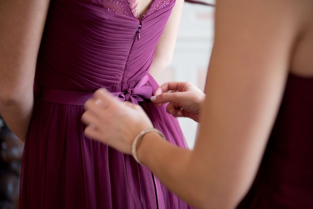 Detail shots of bridesmaids in plum-colored dresses getting ready for the ceremony.