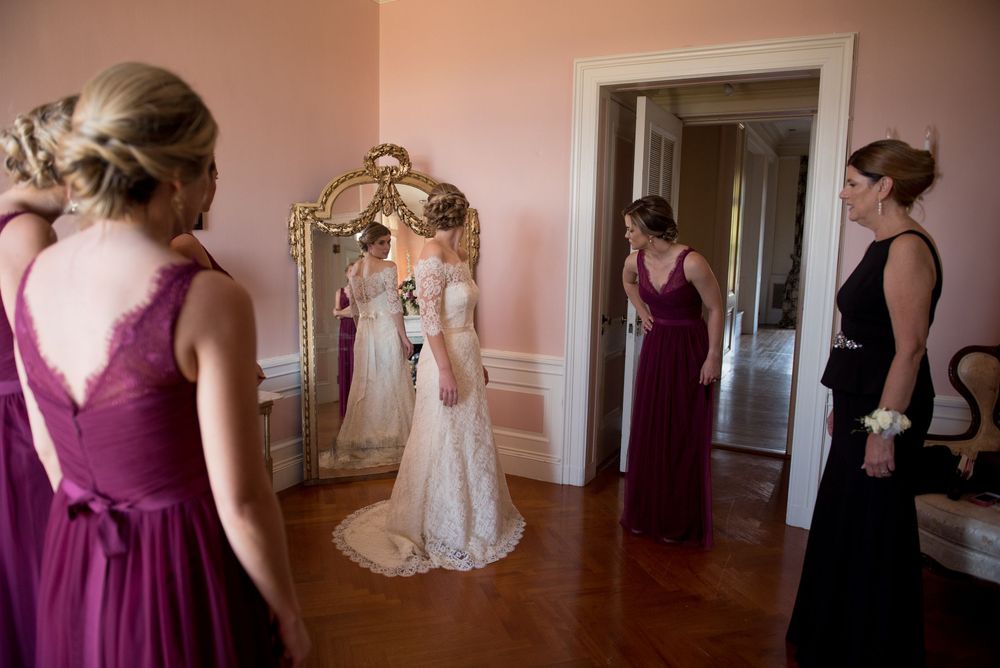 Wedding party in burgundy and black dresses gathered in an elegant room.