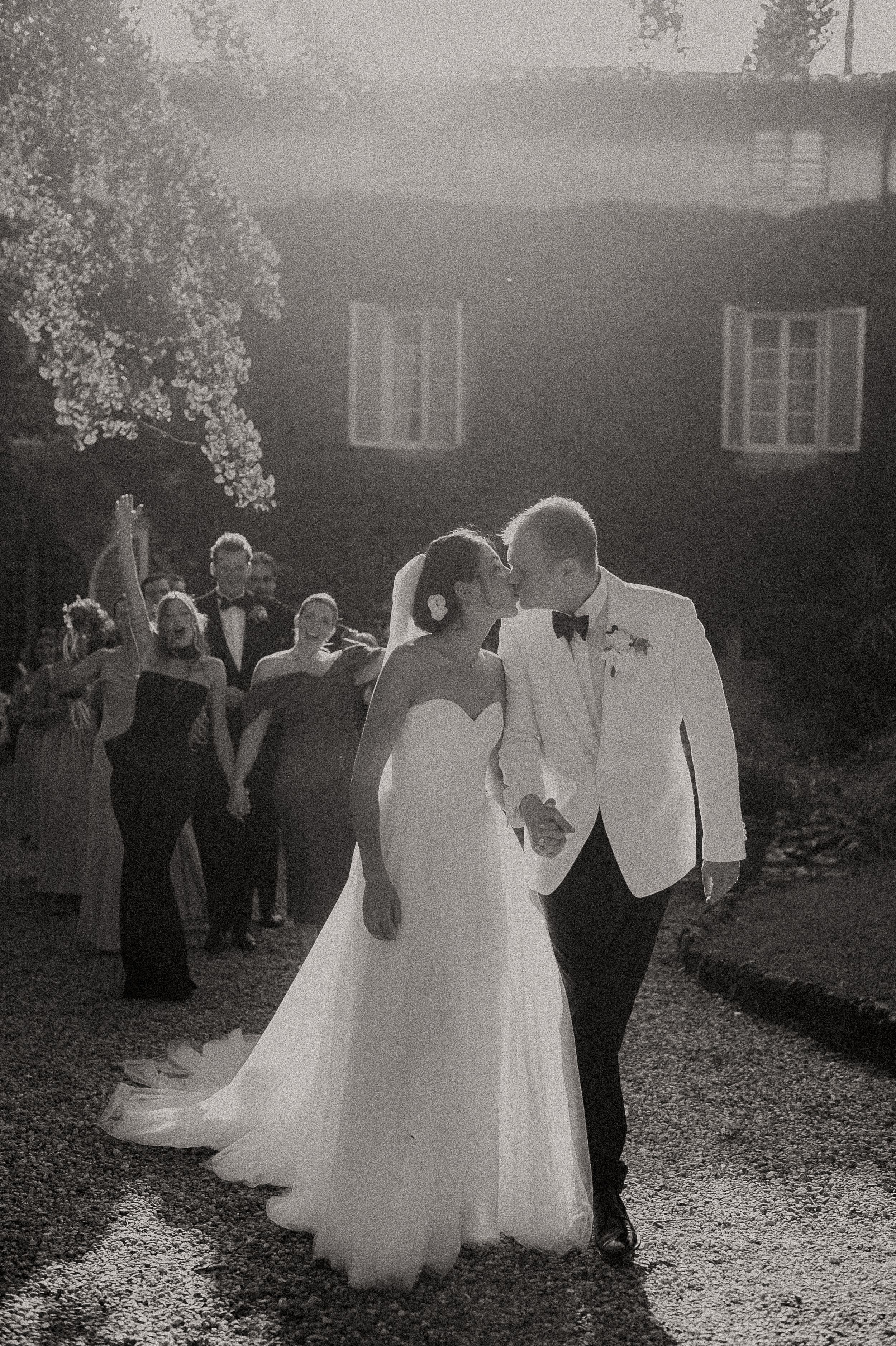 A romantic outdoor wedding celebration with couples dancing in a dreamy black and white shot.