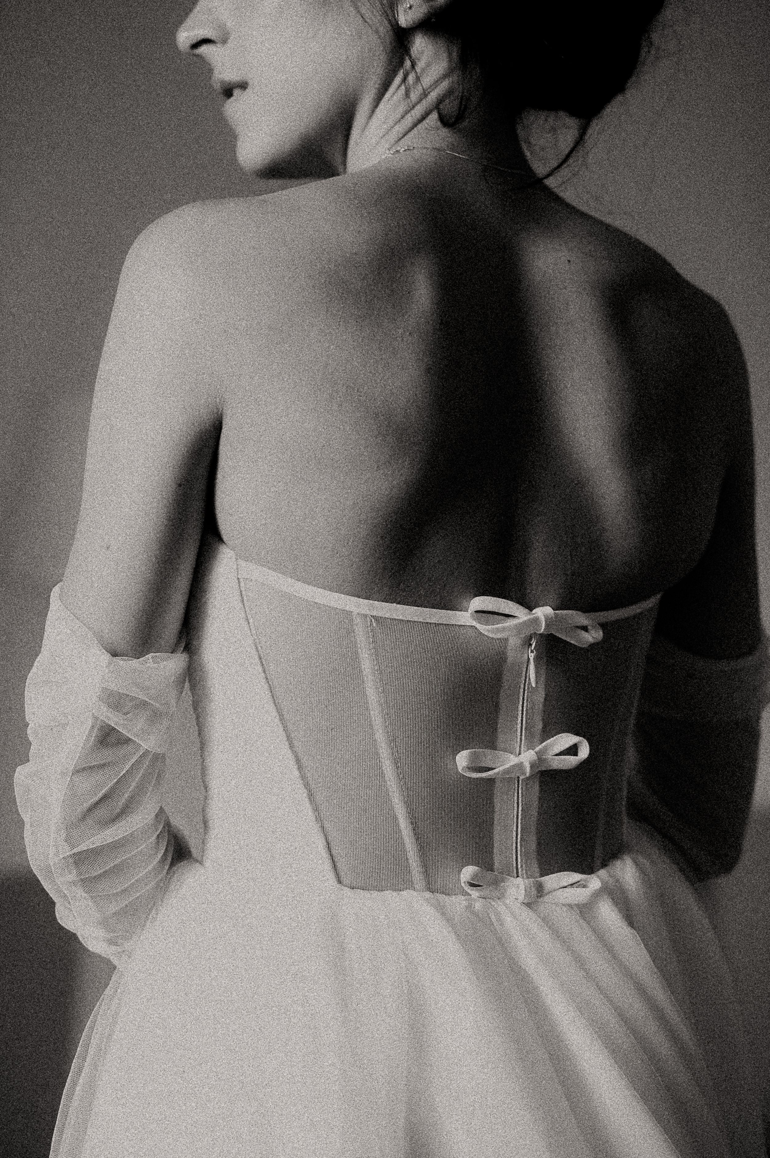 Close-up details of a white wedding dress showing delicate bow-tied corset back.