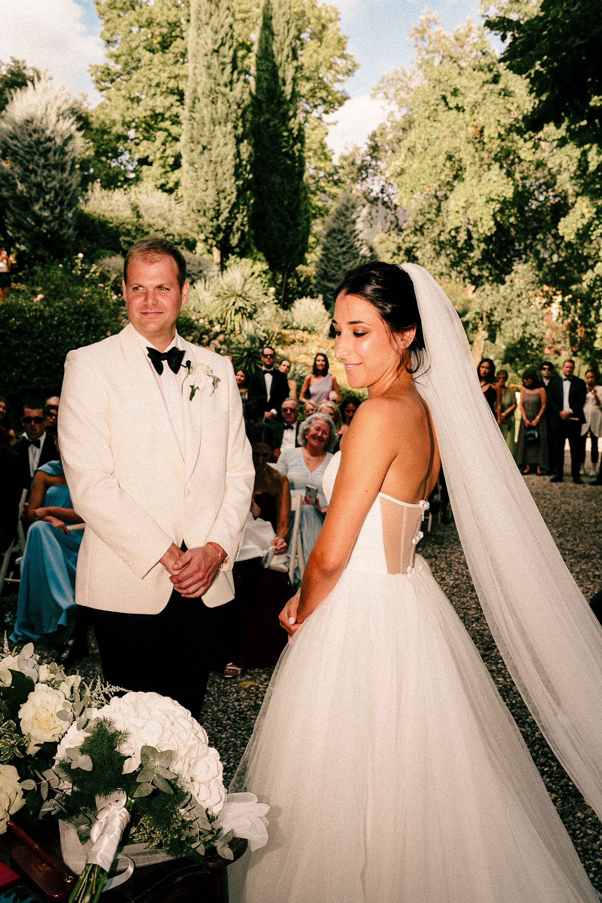 Elegant outdoor wedding ceremony with couple in white formal attire.