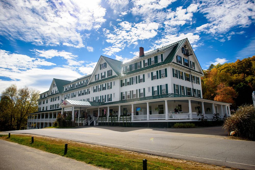 Panoramic view of a grand white colonial-style hotel building with blue sky and clouds.