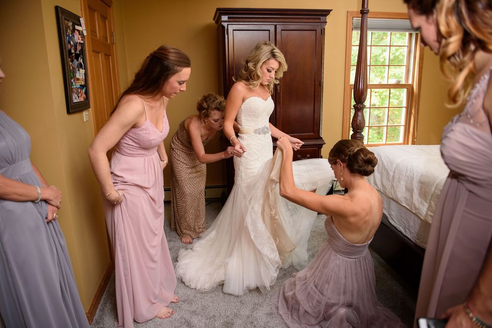 Group in pink and light colored dresses gathered in a room preparing for formal event.