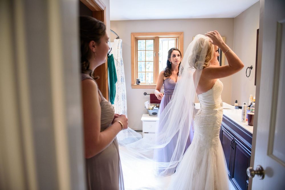 Getting ready scene captured through doorway showing formal dress preparations.